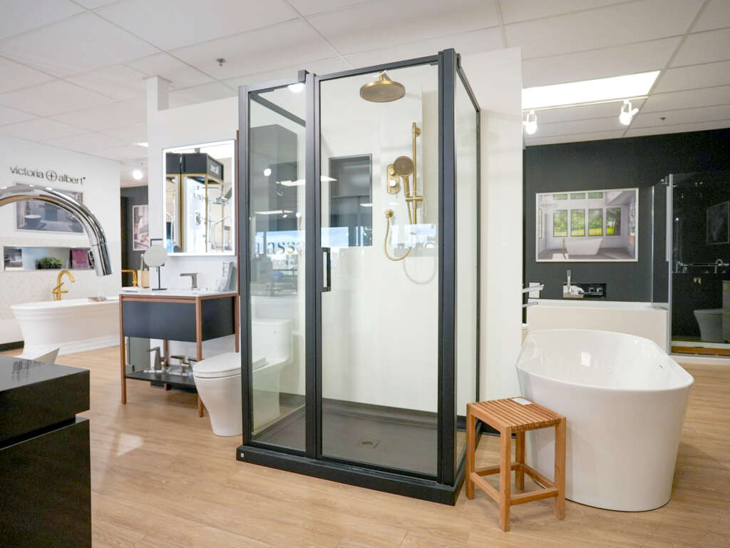 Douche moderne avec quincaillerie en noir et robinet doré, dans la salle d'exposition de Thalassa à Laval
