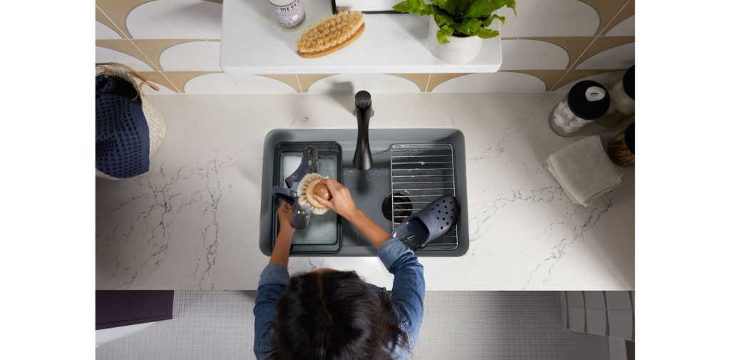 Femme en train de nettoyer la vaisselle dans un évier de cuisine simple en sous surface