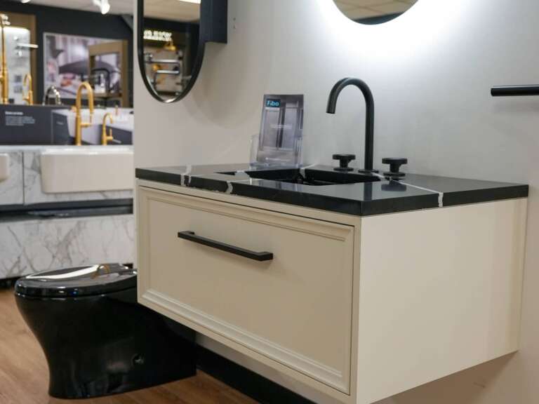 Vue du magasin de plomberie de Laval affichant une vanité blanche, une toilette noire et des éviers de cuisine au fond